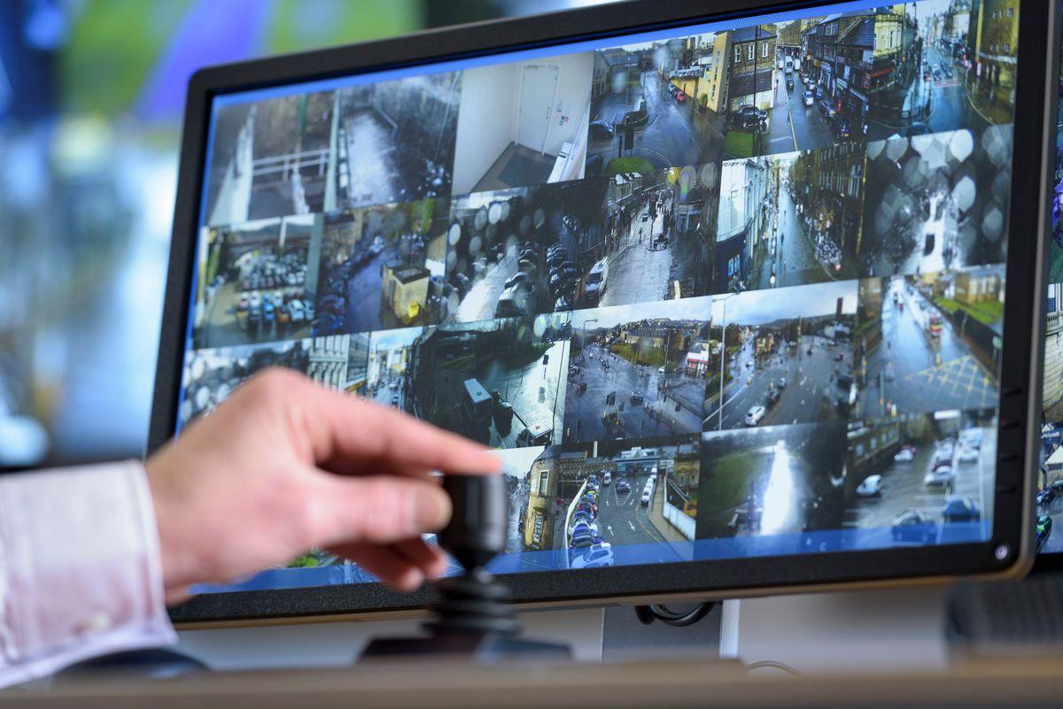 Close up of hand on camera control joystick in control room with video wall